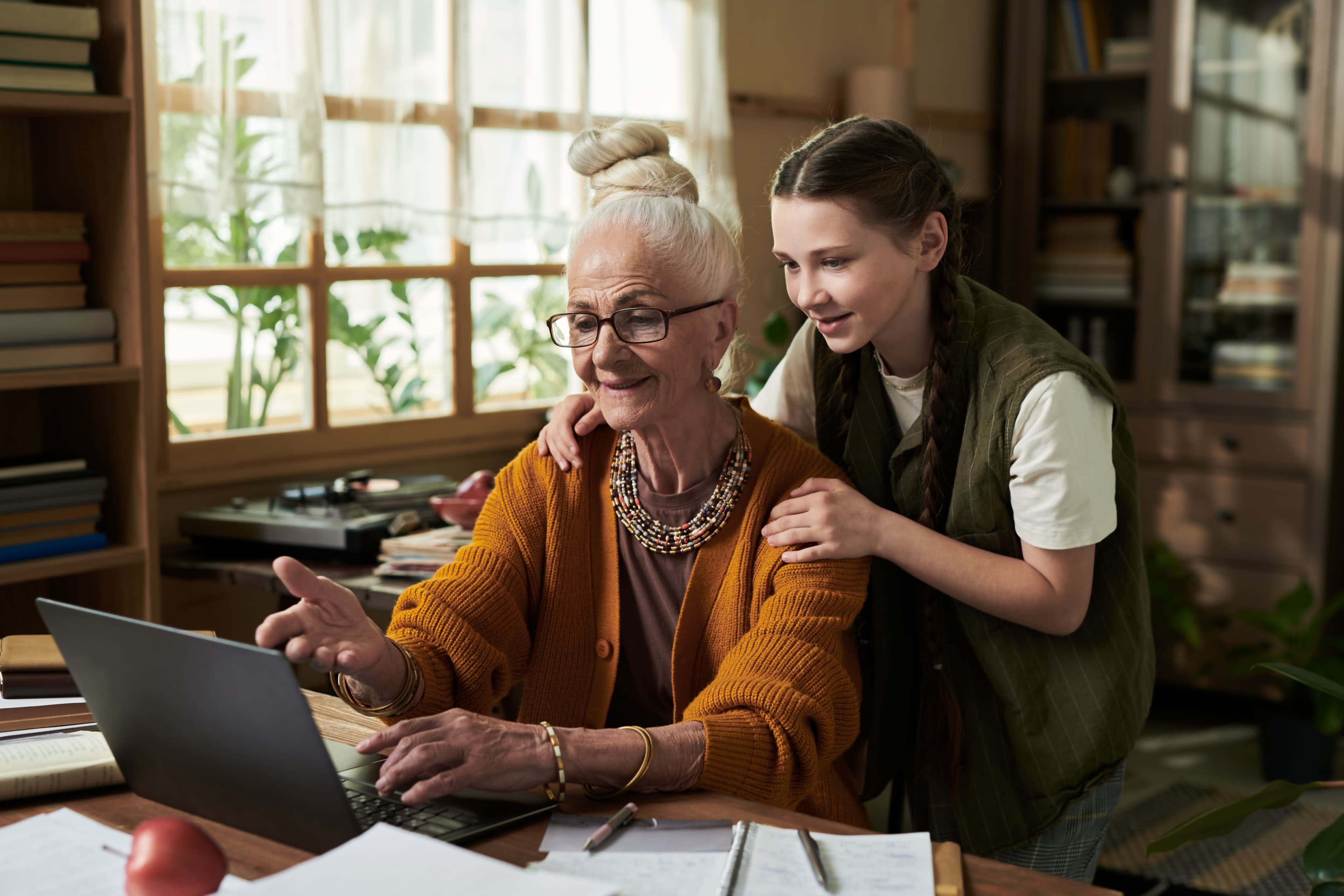 Grandmother sharing her memoir with granddaughter on laptop at home.